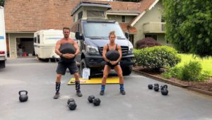 Joe and Emily doing Rogue Strongman Sandbag front squats in the driveway